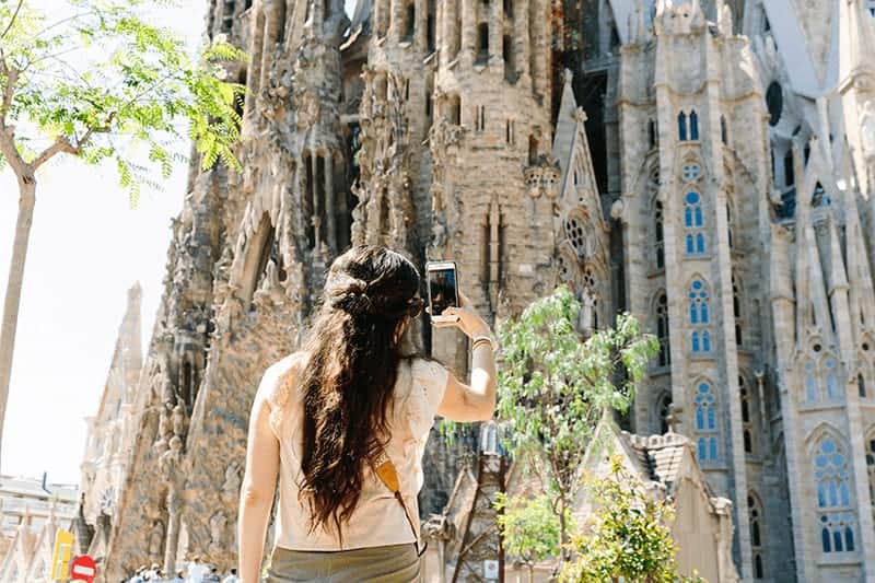 A woman takes a picture of the Sagrada Familia in Barcelona, Spain