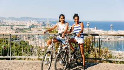 Two girls pose with their bikes on top of Motjuic Hill in Barcelona, Spain