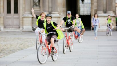 A family rides through the courtyard of the Louvre wearing high-vis vests in Paris, France