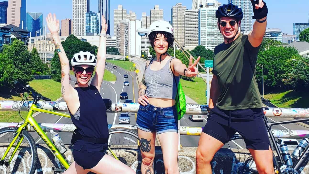 3 bike riders pose on a bridge in Atlanta, Georgia