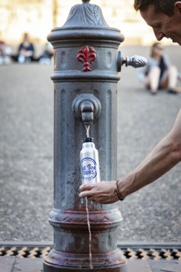 A man fills up his reusable water bottle at a fountain in Florence, Italy