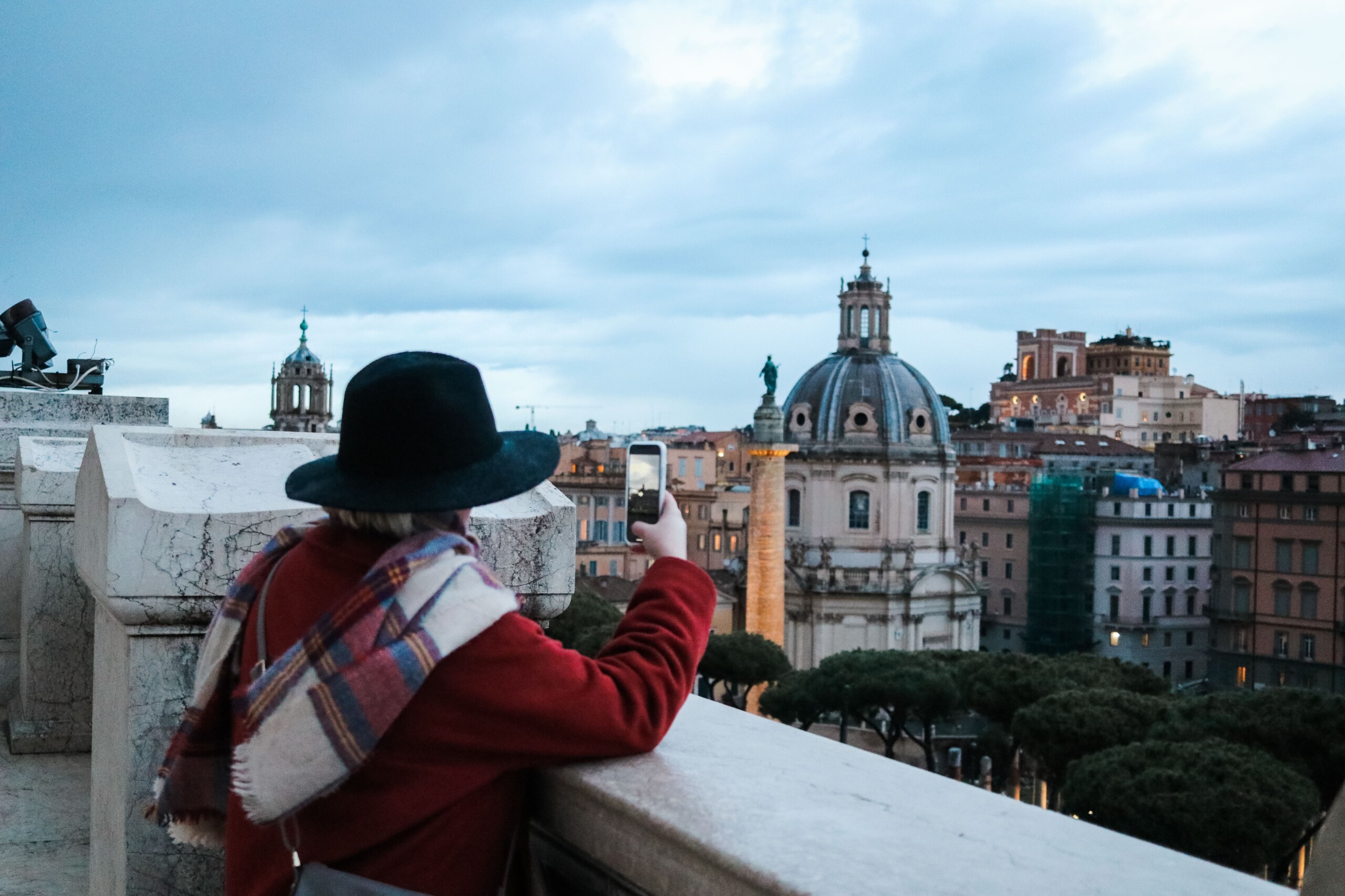 A woman takes a photo looking out over Rome