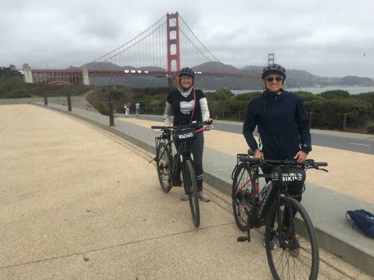 A couple poses with their bikes in front of the Golden Gate Bridge in San Francisco, California
