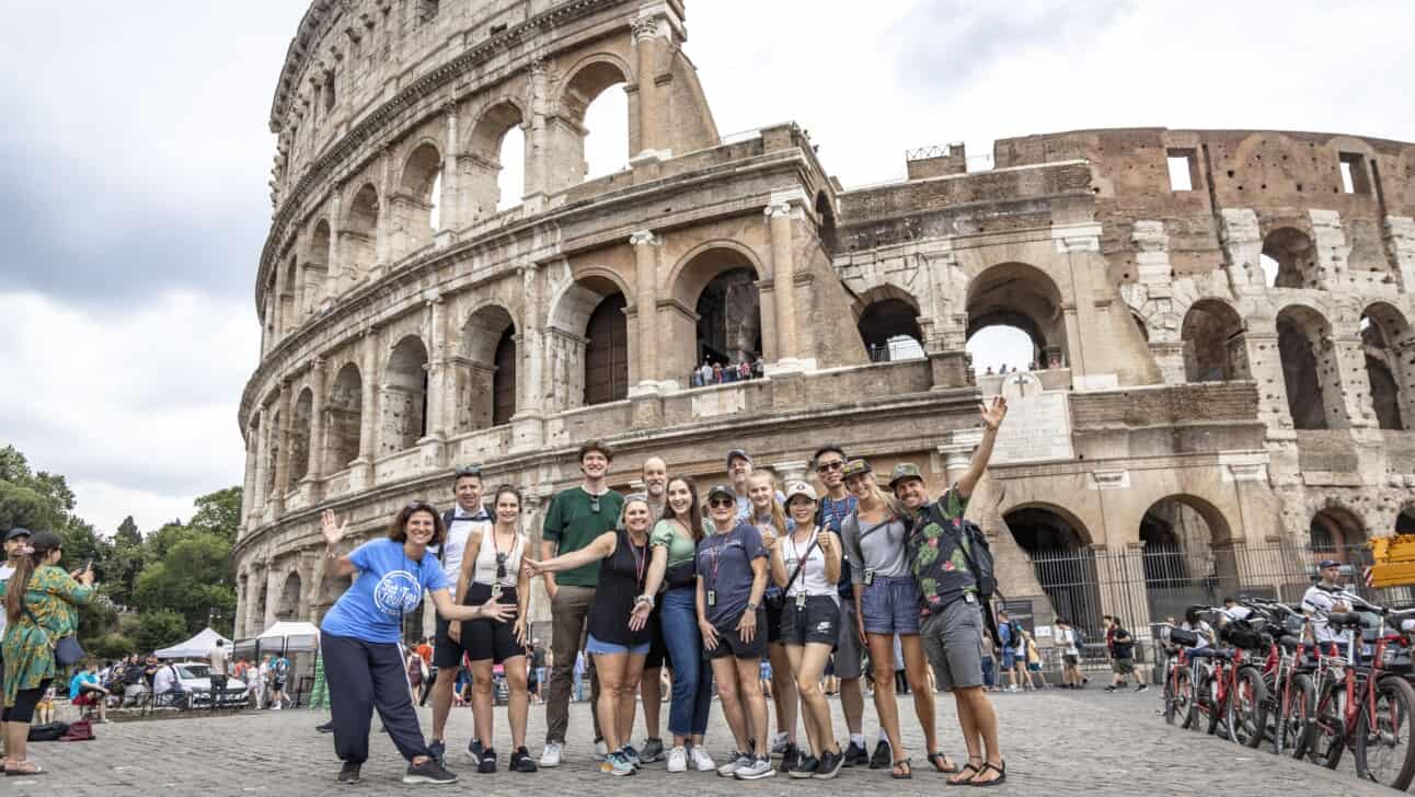 A group poses for a photo in front of the Colosseum in Rome, Italy