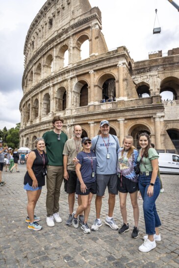 A family poses for a photo in front of the Colosseum in Rome, Italy