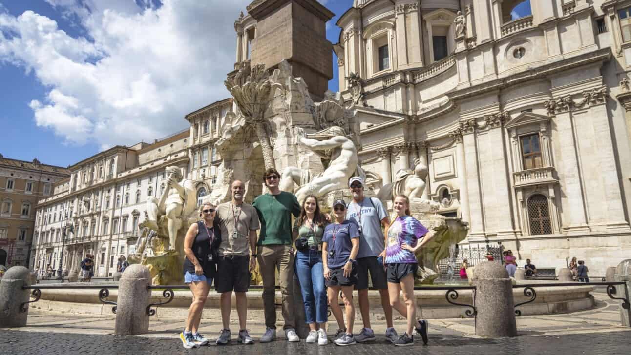 A family poses for a photo in front of the Navona fountain in Rome, Italy