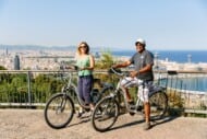 A couple poses with e-bikes on Montjuic hill in Barcelona, Spain