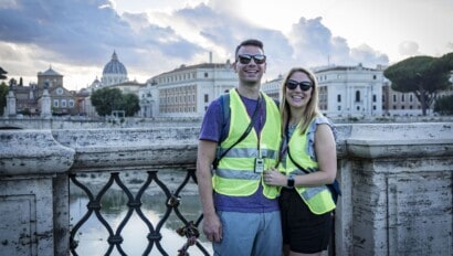 A couple poses on a bridge with St. Peter's Basilica in the background