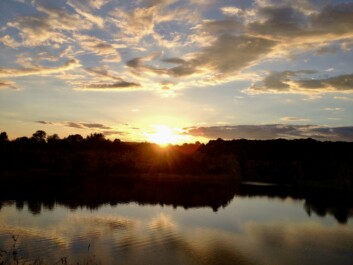 The sun rises over a lake outside Krakow, Poland