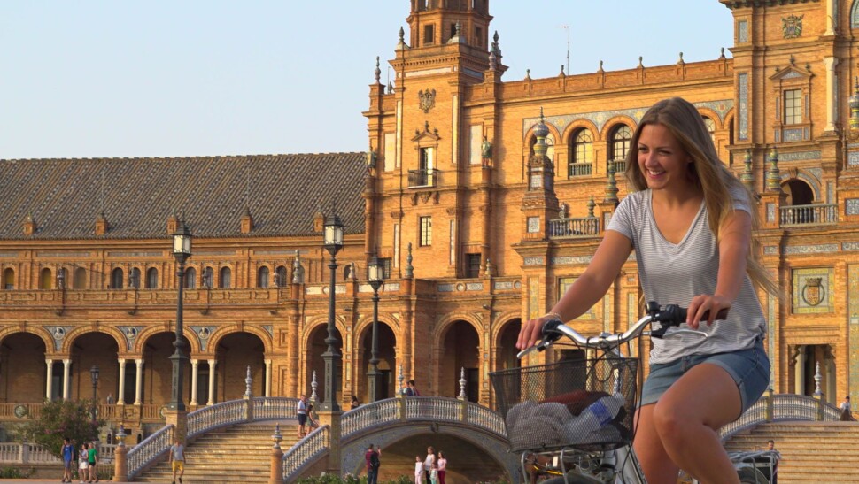 a girl laughs while riding her bike through seville