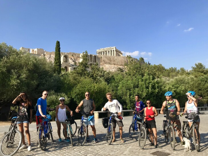 A group of cyclists pose in front of the ruins in Athens, Greece