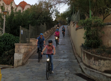 A group of cyclists ride down a stone-paved hill in Athens, Greece