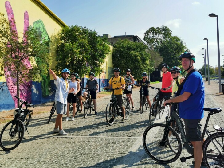A group of cyclists listen to the guide explaining the Kez street art in Athens, Greece