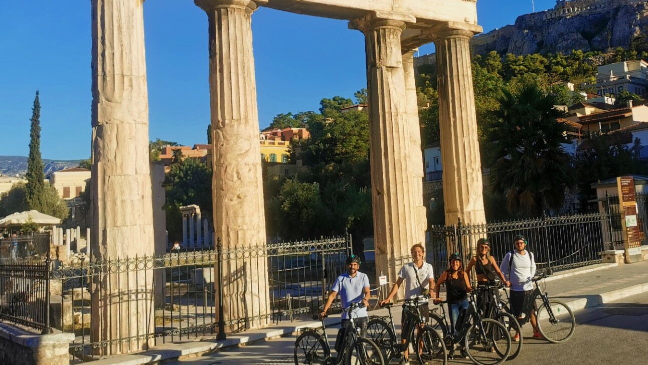 A group of cyclists pose for a photo in front of the Olympian Zeus in Athens, Greece