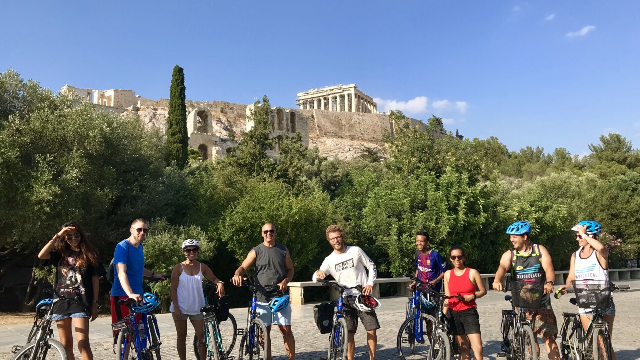 A group of cyclists pose for a photo in front of the Acropolis in Athens, Greece