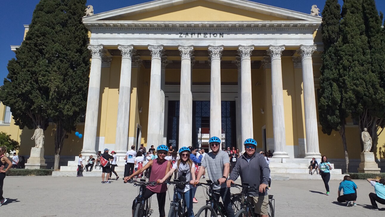 A group of cyclists pose for a photo in front of Zappeion Hall in Athens, Greece