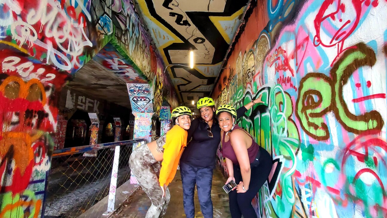 Three friends pose for a photo in the grafittied Krog Tunnel in Atlanta, Georgia