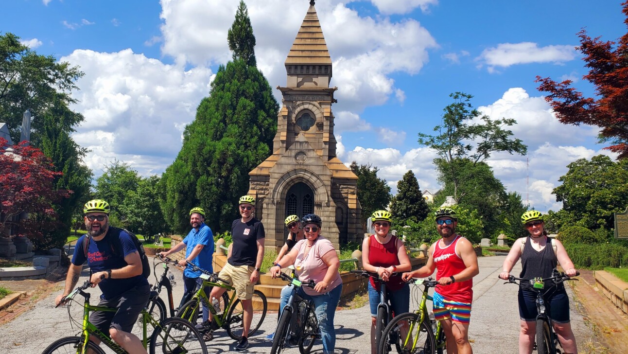 A group of cyclists pose for a photo at the entrance of the Oakland Cemetery in Atlanta, Georgia
