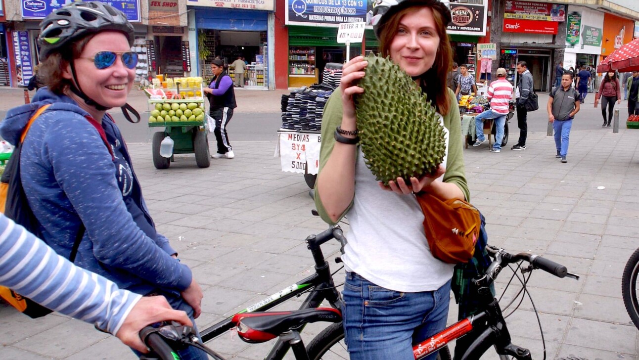 A women holds up a durian fruit outside the market in Bogota, Colombia