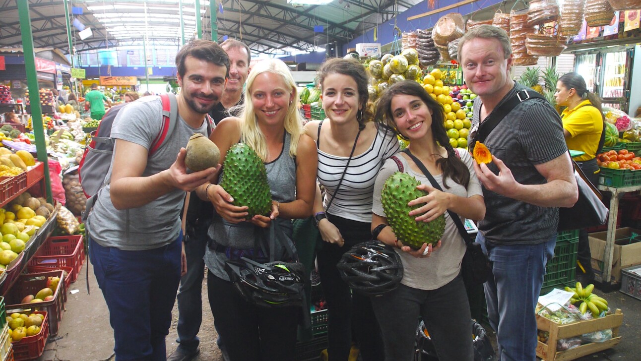 A group of friends pose for a photo with exotic fruit at the Merced in Bogota, Colombia