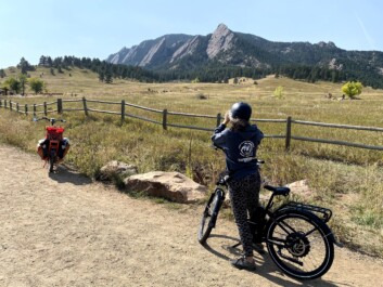 A female cyclist takes a picture of the Rocky Mountains in Boulder, Colorado