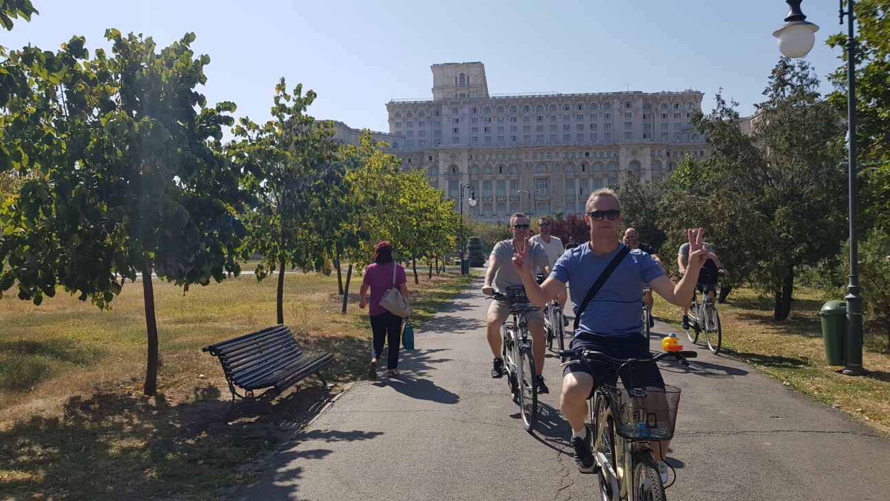Cyclists ride in front of the Palace of Parliament in Bucharest, Romania