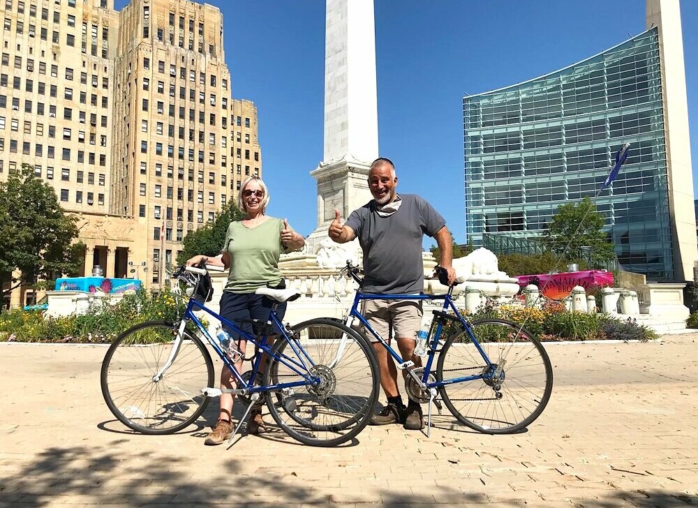 A couple poses for a photo with their bikes in front of the McKinley Monument in Buffalo, New York