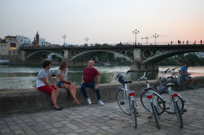 friends enjoy a break after biking along the river in seville