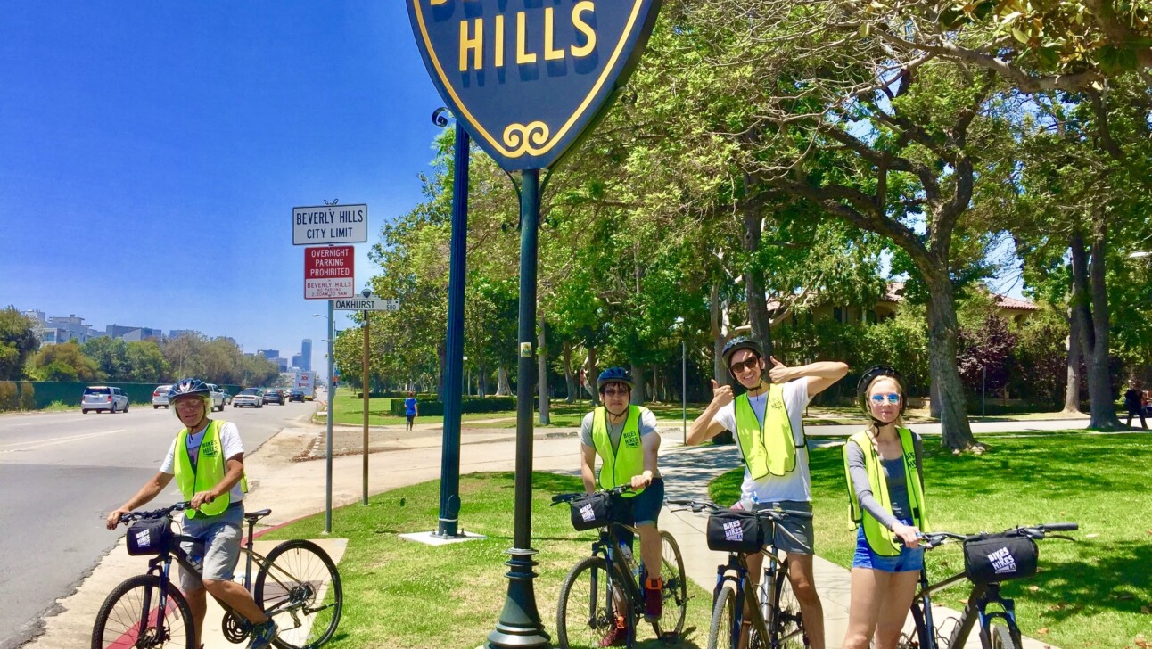 Cyclists pose for a photo in front of the famous Beverly Hills sign in Los Angeles, California