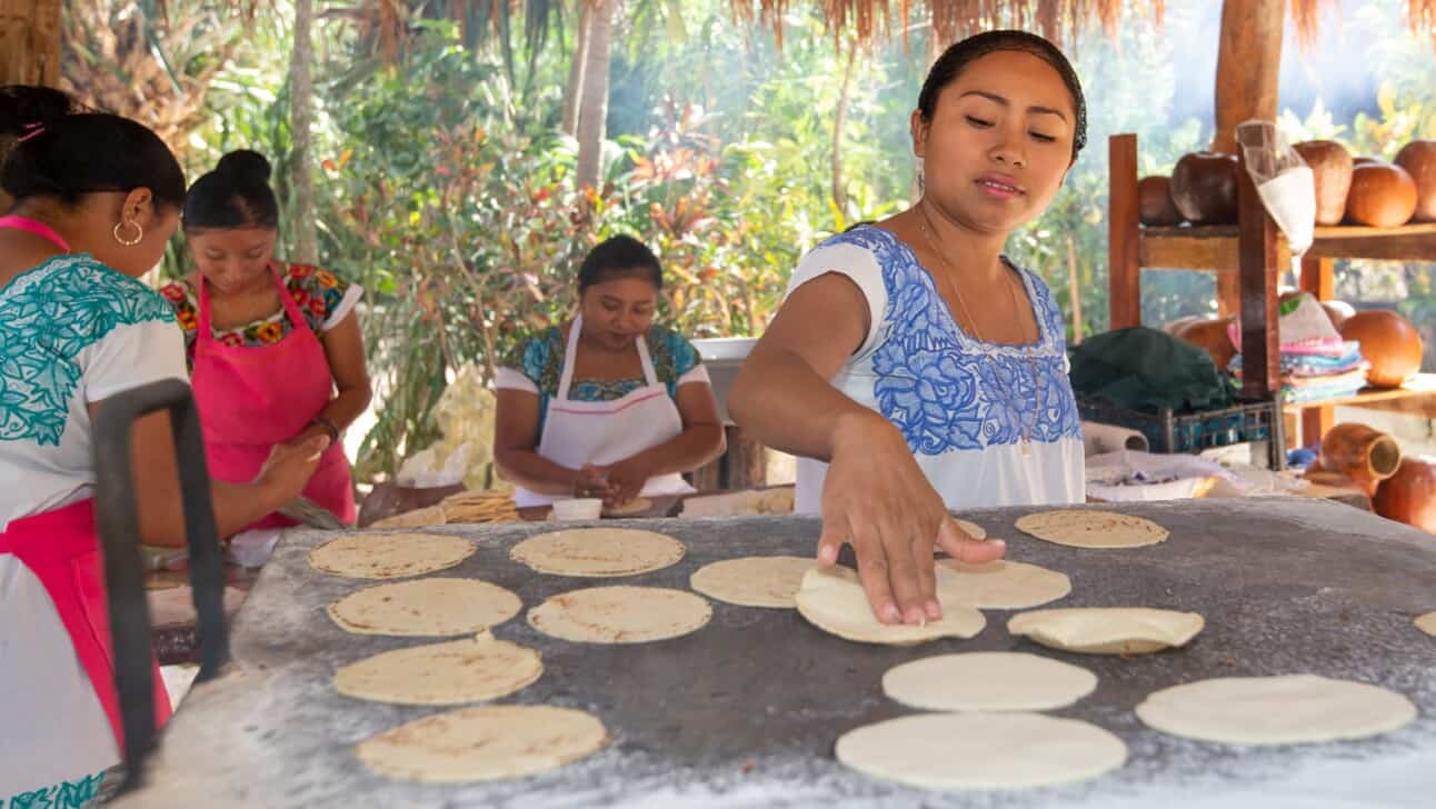 A woman makes fresh tortillas on a hot griddle during brunch in the jungle