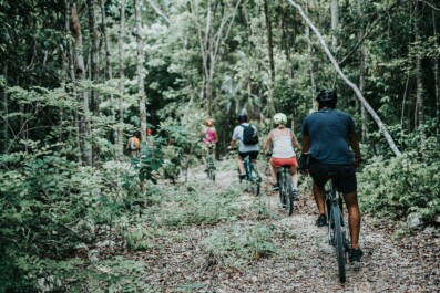 Cyclists ride among the trees in Tulum, Mexico