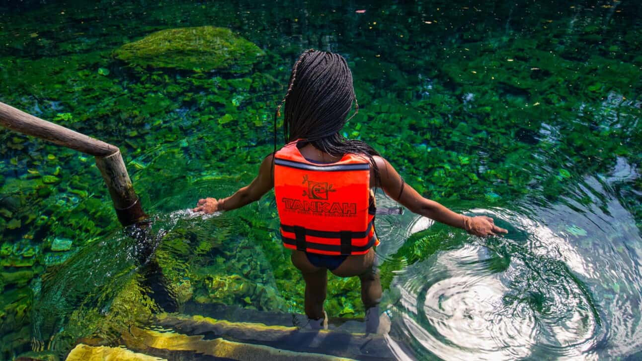 A young girl takes the stairs down into a Cenote to swim in Tulum