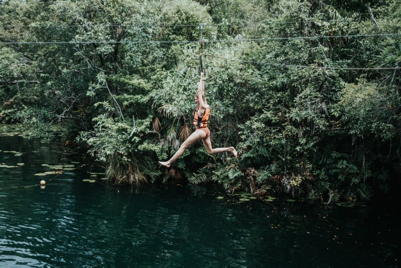 A women ziplines above a cenote in Tulum, Mexico