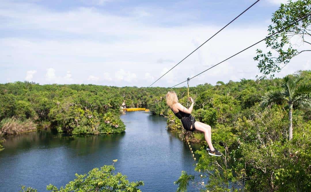 A woman ziplines over a cenote in Tulum