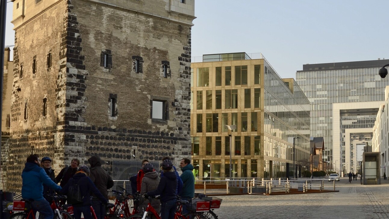 A group of cyclists stop to learn about the medieval tower in Cologne, Germany