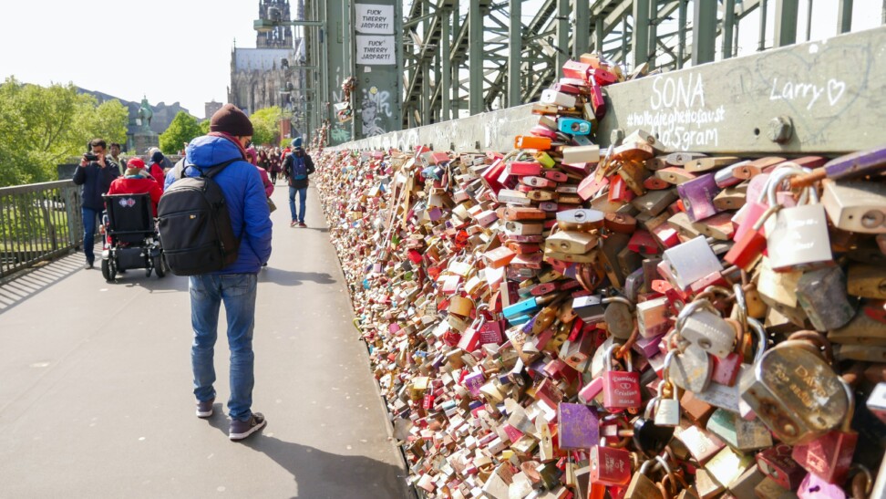 A man walks along colorful locks on a bridge in Cologne, Germany