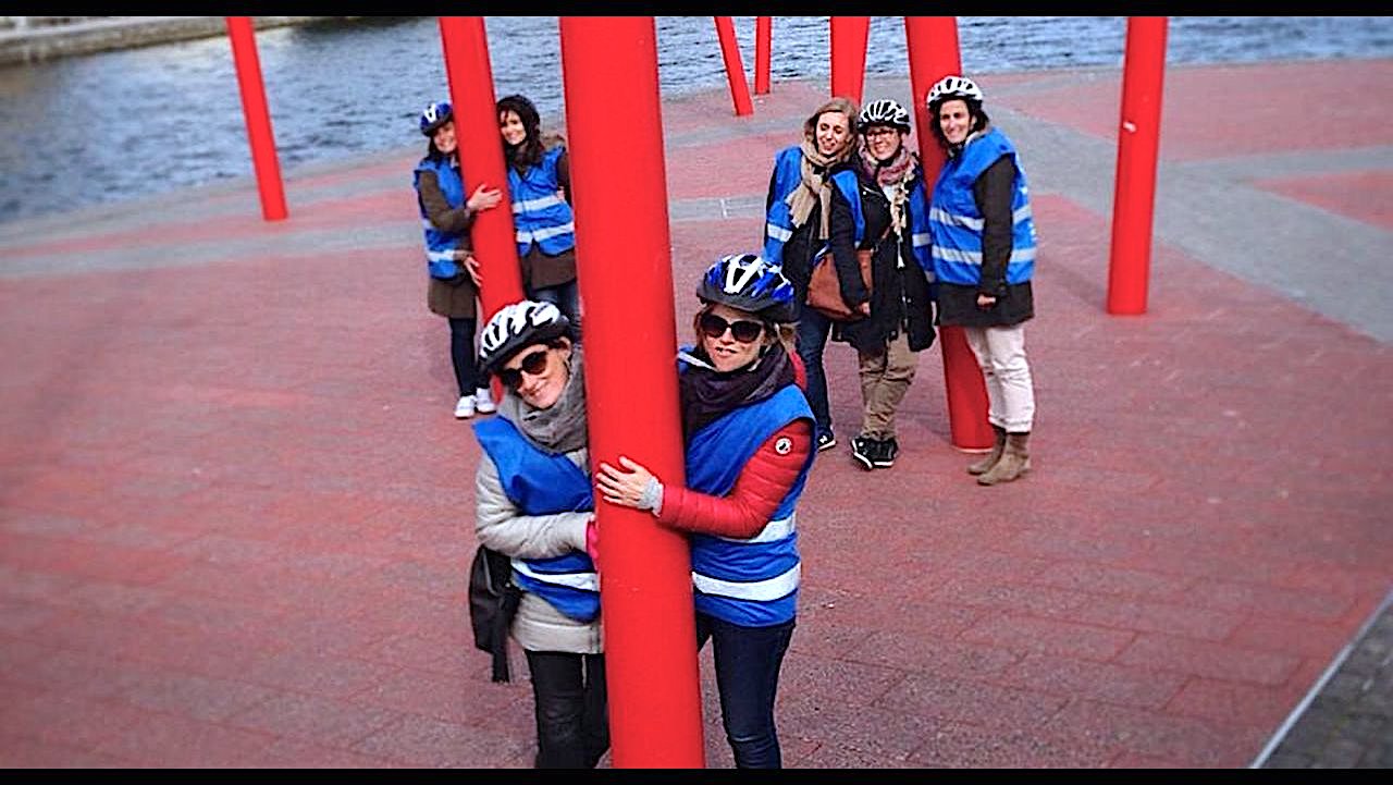A group of friends pose with the red poles in Grand Canal Square in Dublin, Ireland