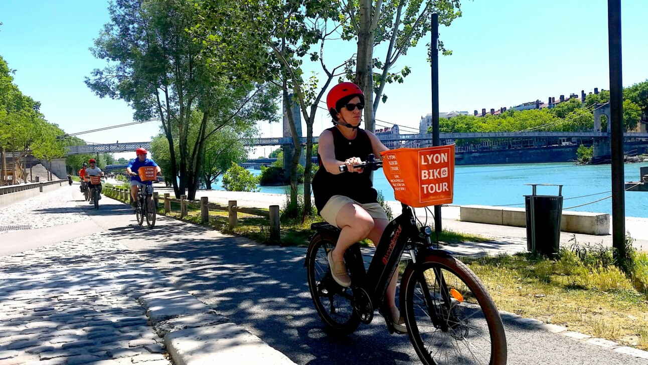 A female cyclist rides along the Rhone River in Lyon, France