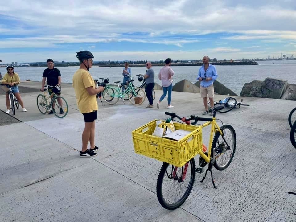 A group of cyclists stop at the beach to see the breakwall in Newcastle, Australia