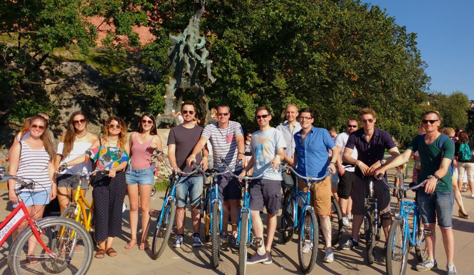 A group of cyclists in front of the Wawel Dragon statue in Krakow, Poland