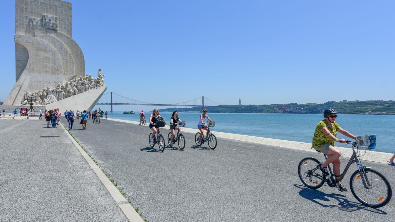 Cyclists ride along the sea in Lisbon, Portugal