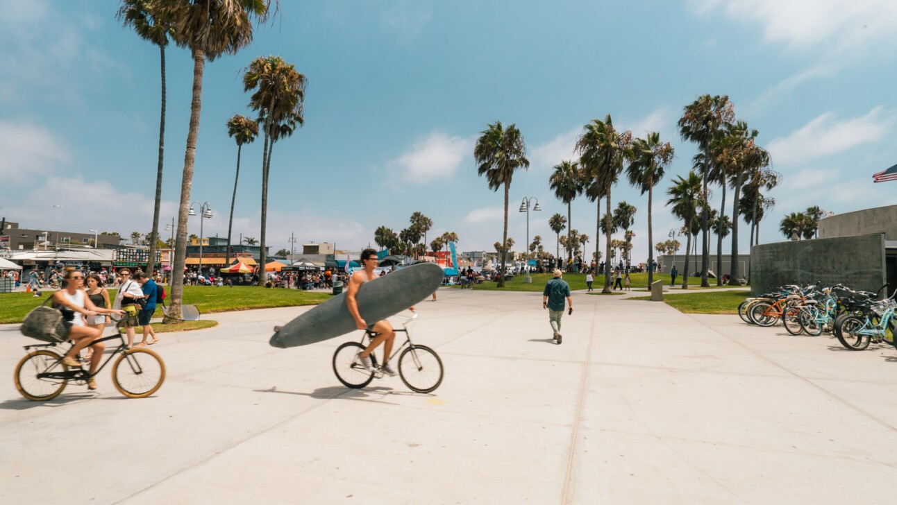 Surfers ride their bike with their surfboards at the beach in Los Angeles, California