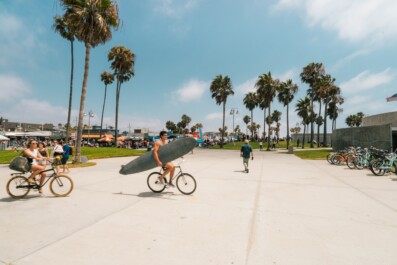Surfers ride their bike with their surfboards at the beach in Los Angeles, California