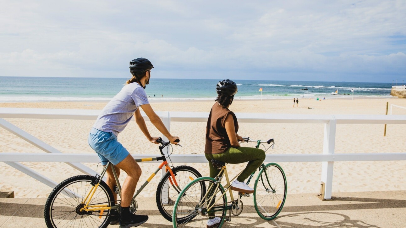 Cyclists ride along Nobbys beach towards the lighthouse