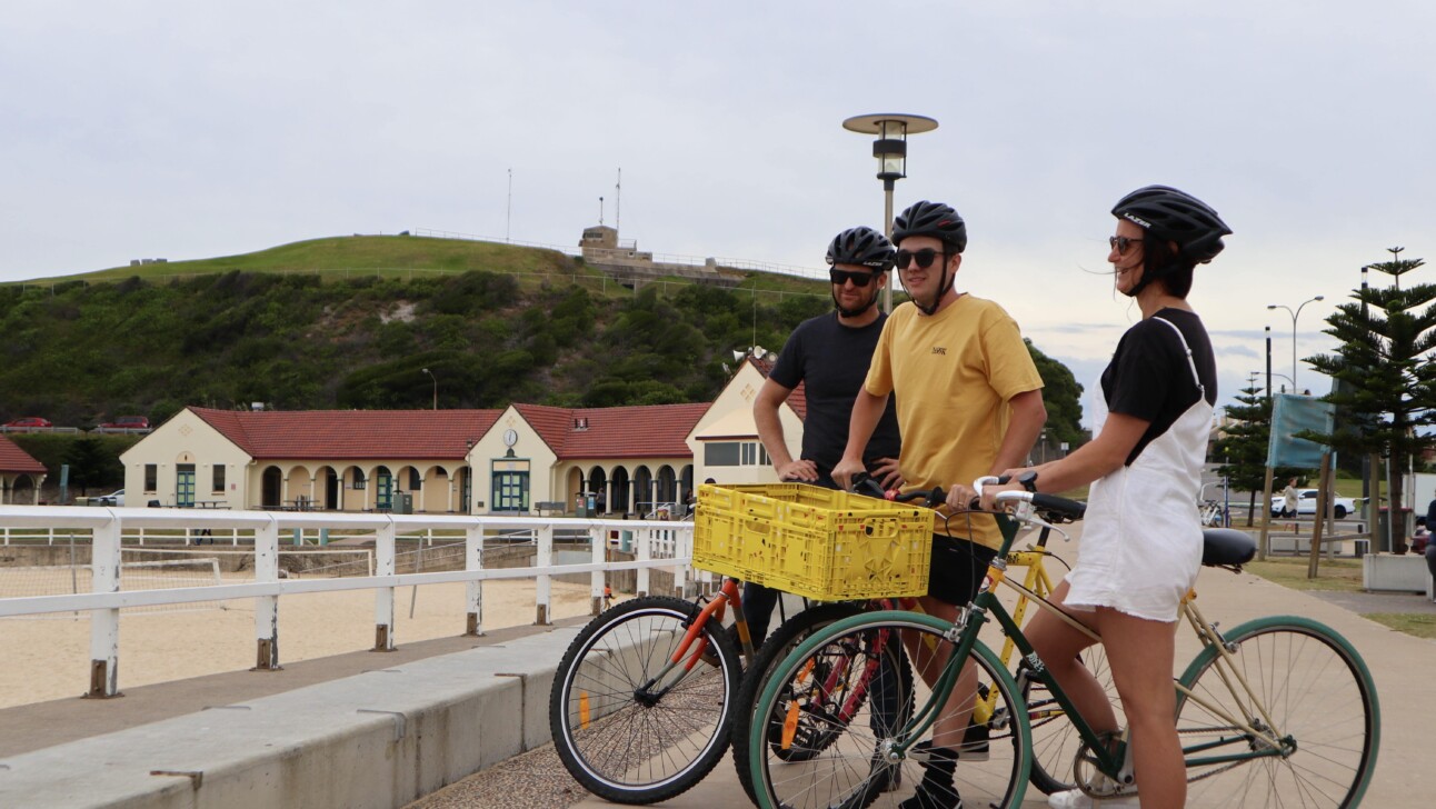 Cyclists look out towards views of the breakwall in New Castle, Australia