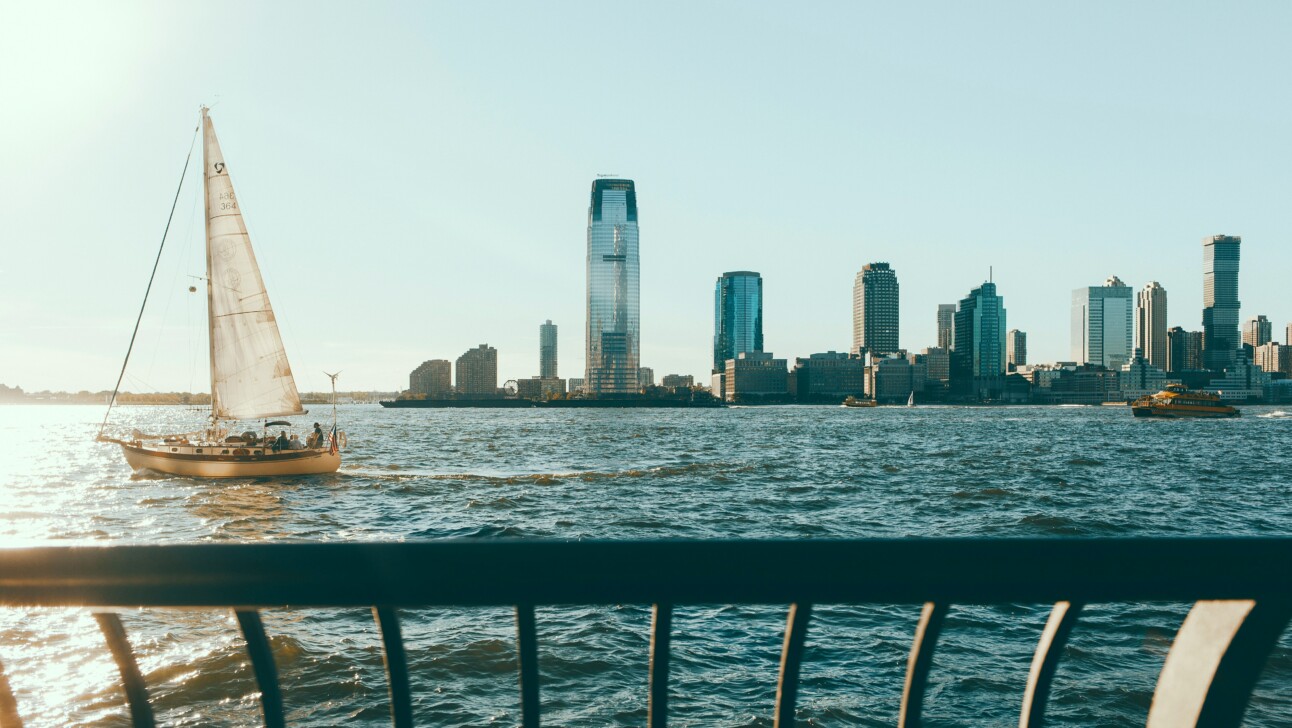 A view of New Jersey with a sailboat in the water from Battery Park, New York City