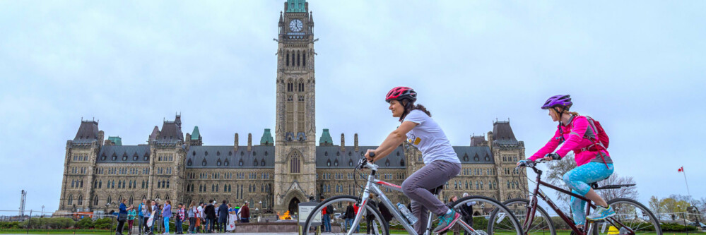 Cyclists ride in front of the Parliament Building in Ottawa, Canada