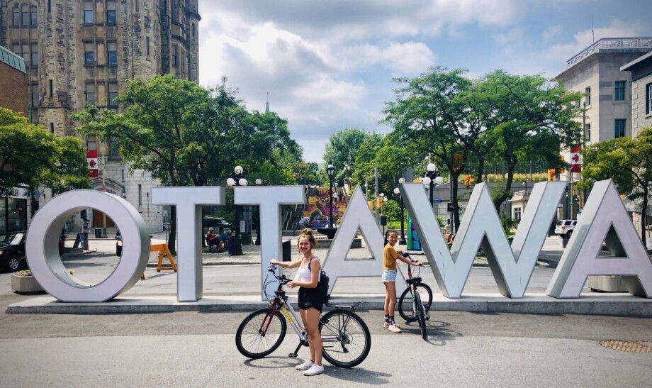 Cyclists pose with their bikes in front of the Ottawa sign in Canada