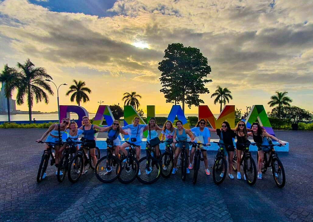 A group of cyclists in front of the Panama sign in Panama City