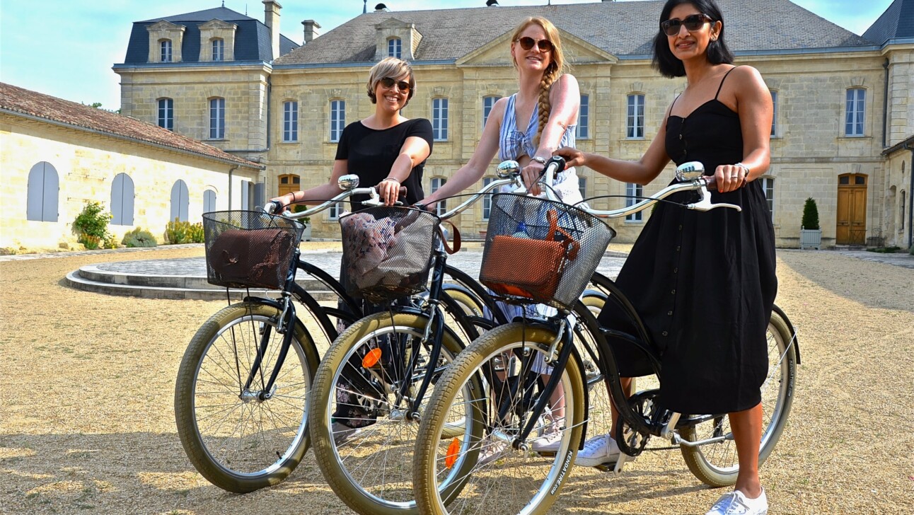 A group of friends pose for a photo on their bikes in front of Chateau Soutard